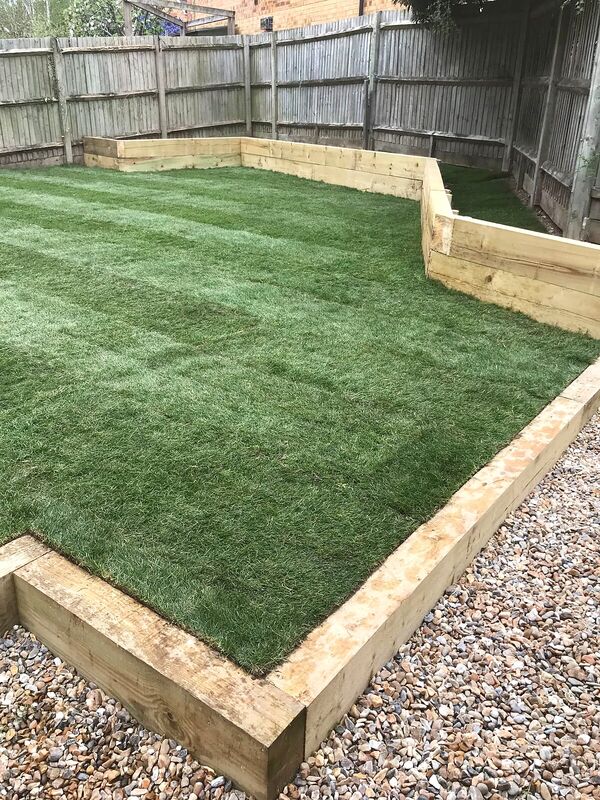 Newly laid lawn edged with timber sleeper retaining and a gravel border