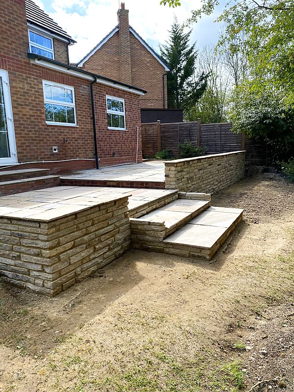 Sandstone patio on two levels with natural stone retaining walls and wide steps