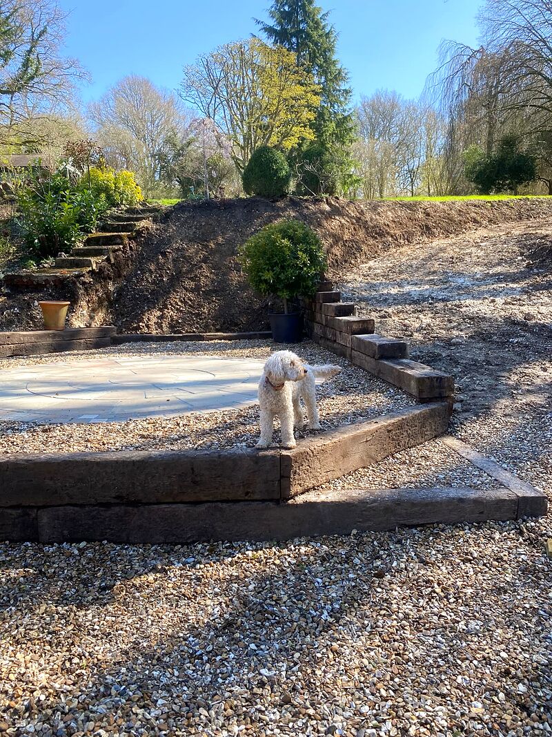 Sandstone paving circle set in gravel framed by heavy timber sleeper retaining on a sloping garden