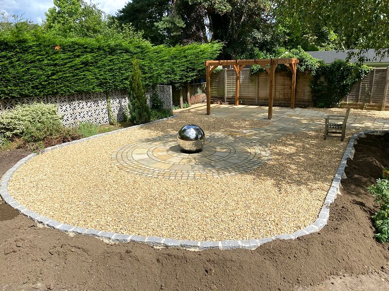Gravel garden with granite sett edging, a sandstone circle, a sphere water feature and a timber pergola