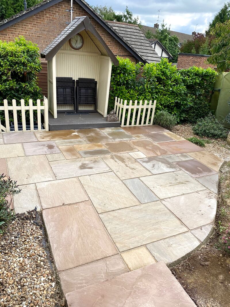 Mixed-tone sandstone patio with a curved edge leading to a timber garden arbour