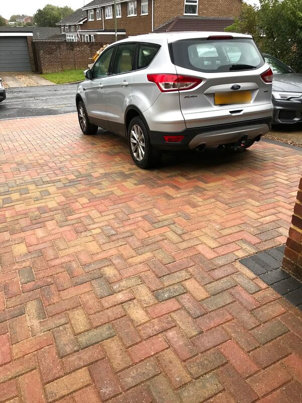 Block paved driveway laid in a herringbone pattern with a car parked on it