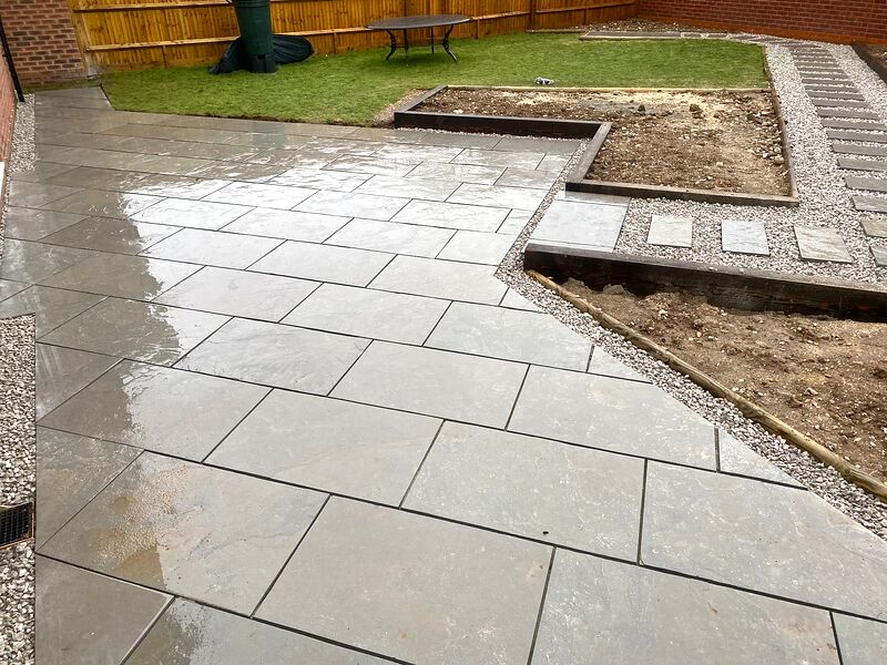 Grey paved patio with gravel margins and timber sleeper raised beds