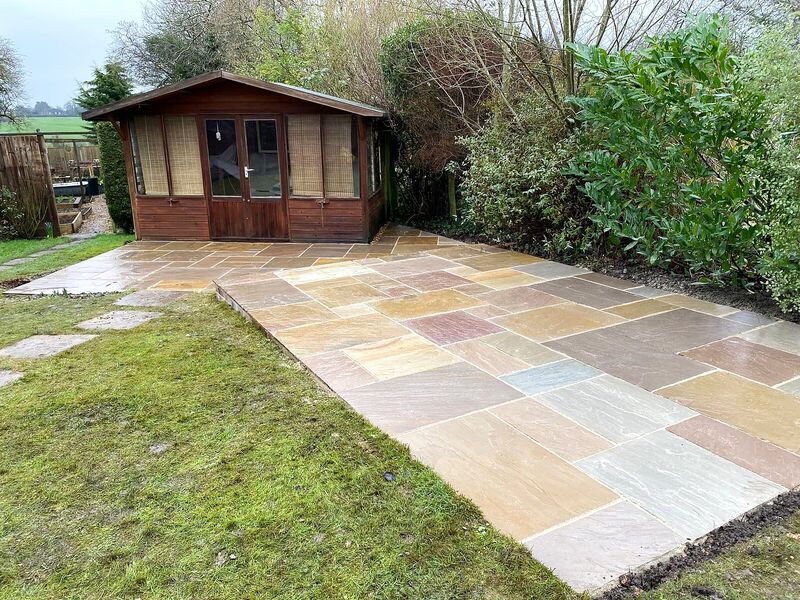 Indian sandstone patio laid in front of a timber summerhouse in an English garden