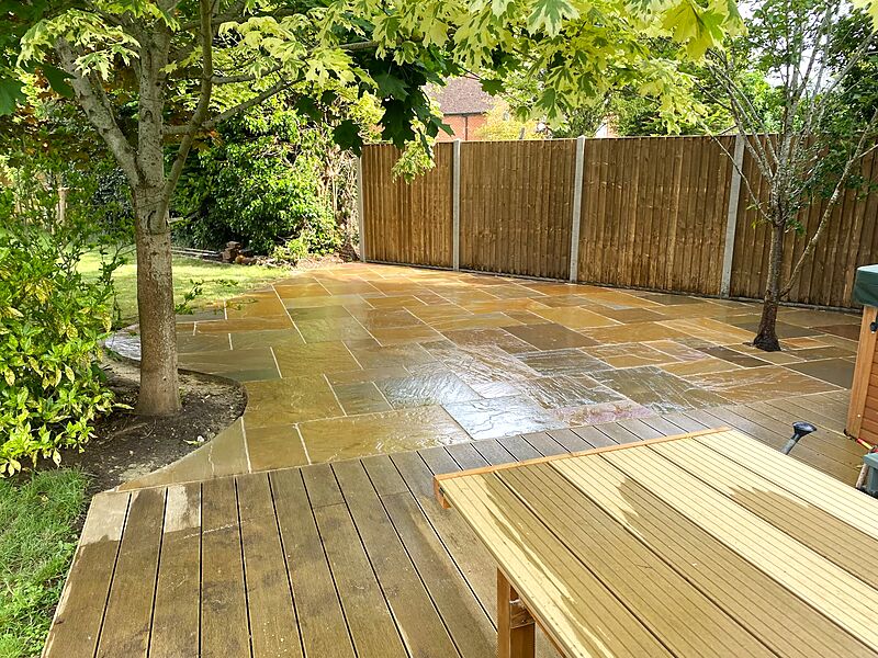 Sandstone patio and timber decking laid around established trees with new fencing