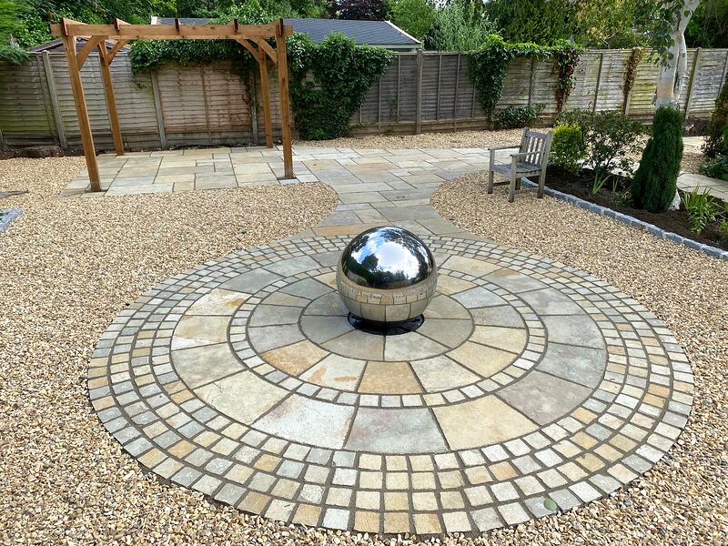 Sandstone paving circle with cobble banding around a polished sphere water feature