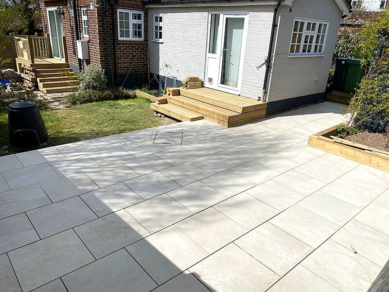 Pale porcelain patio with timber decking steps leading to a house door