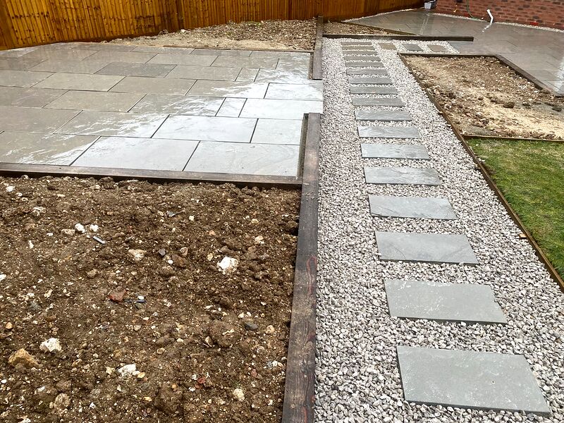 Stepping stone path set in gravel with timber sleeper edging beside a grey patio